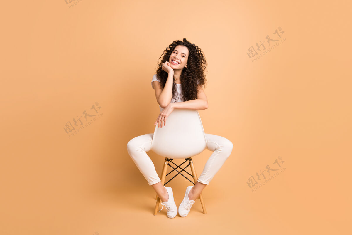 运动鞋全尺寸照片惊人的女士坐在舒适的椅子两腿之间良好的心情启发 开始工作日穿休闲服隔离米色粉彩背景表情漂亮模特