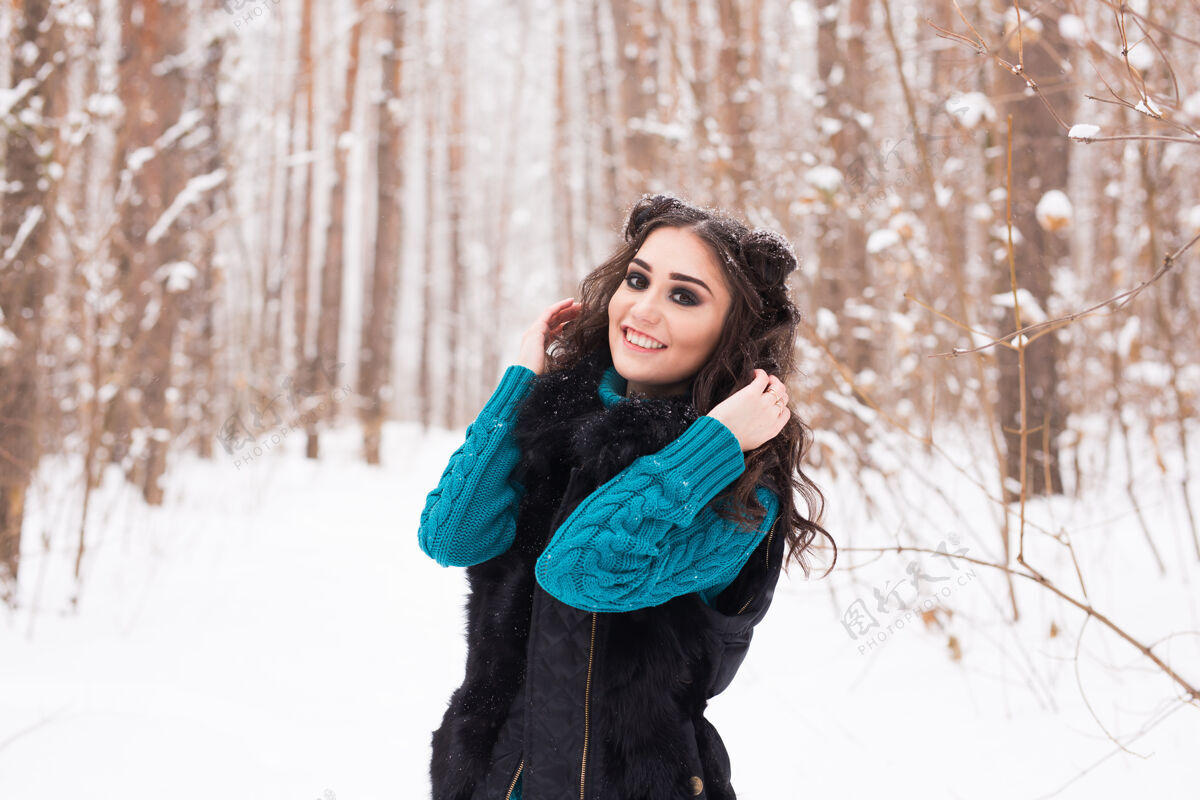圣诞节美丽的年轻女子行走在冬雪的大自然中微笑风帽明亮