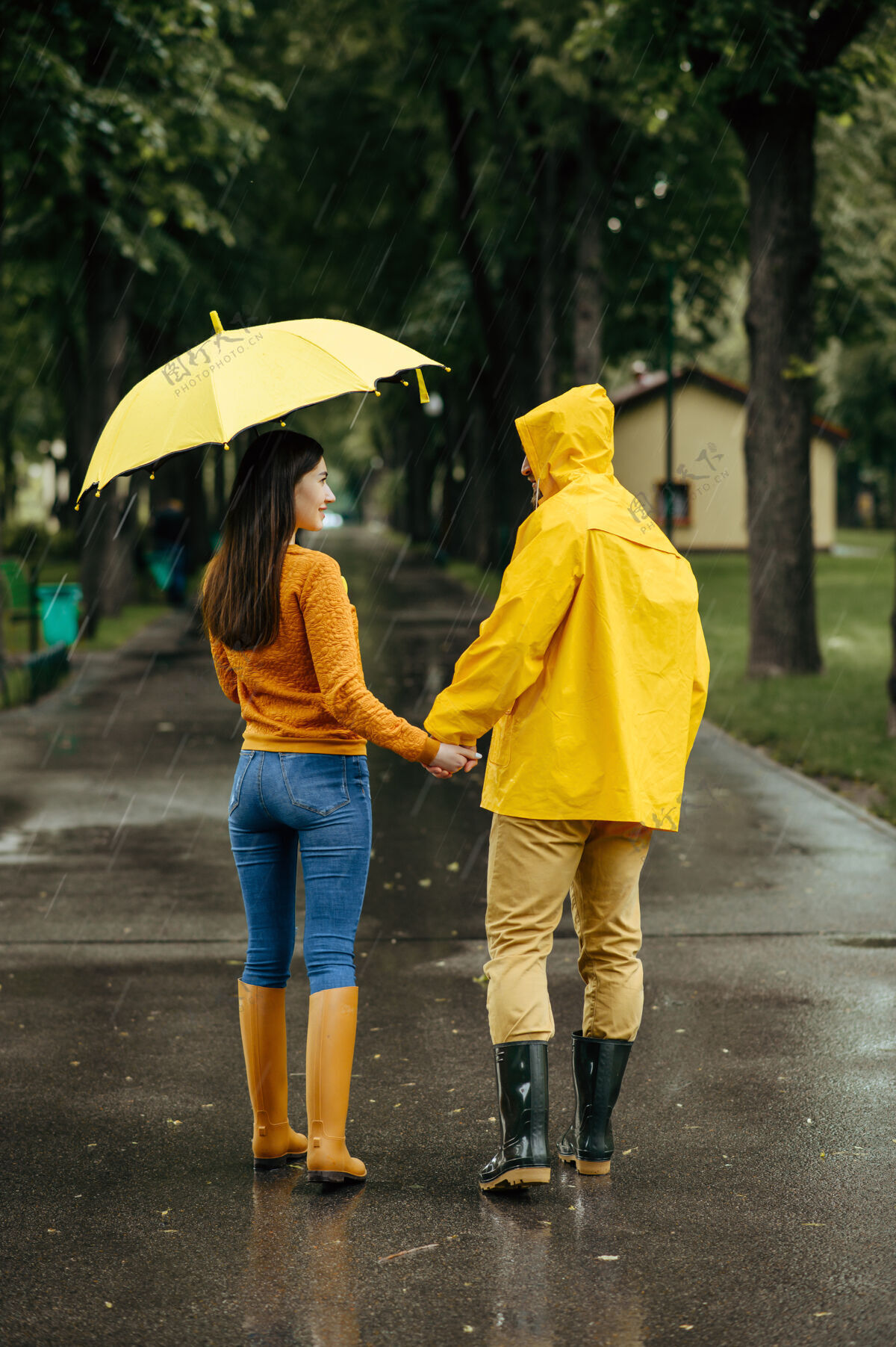 一对雨天 一对恋人撑着伞在公园散步戴曼穿着胶靴的女人走在小路上 小巷里天气潮湿自然女性男朋友