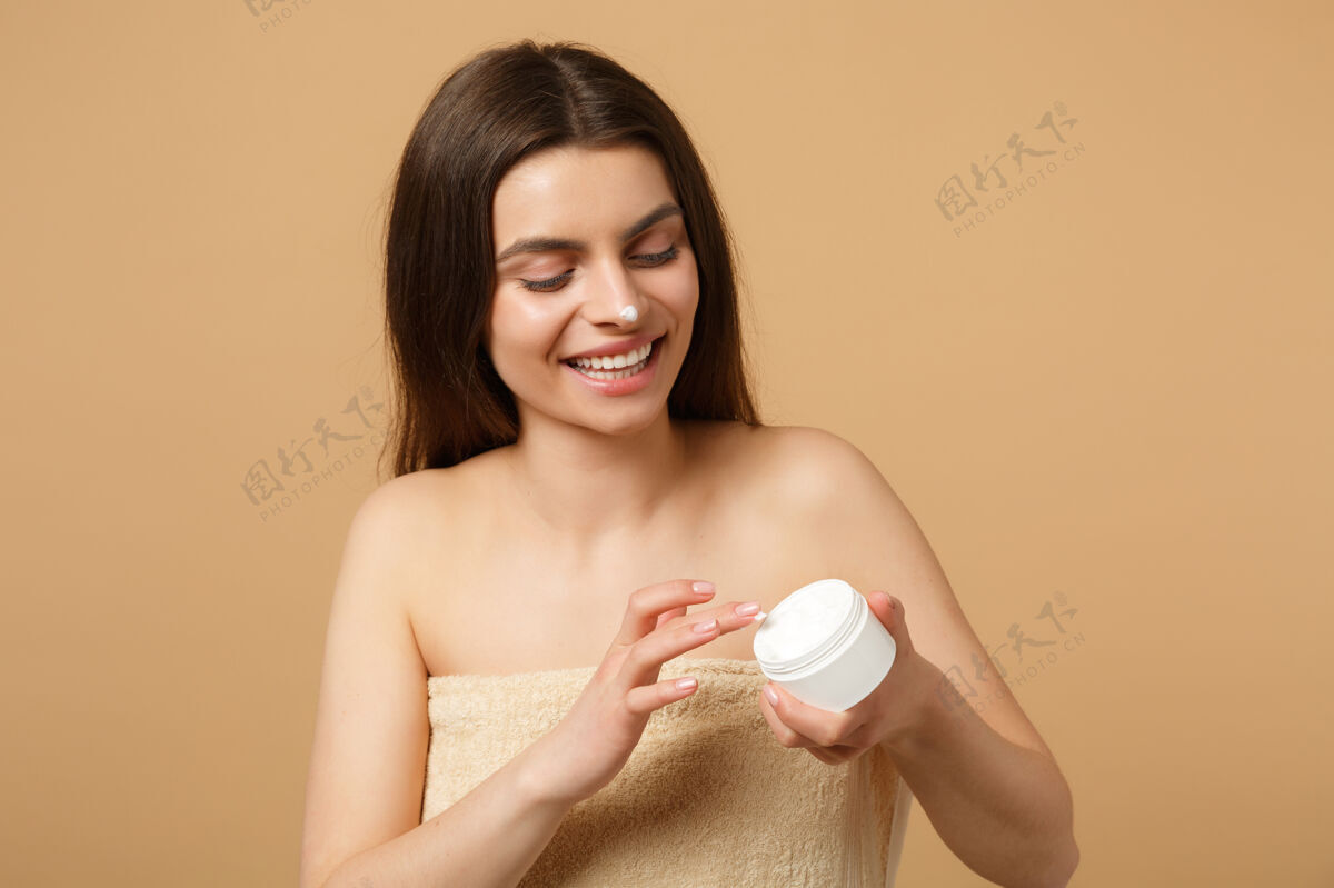 包装近景半裸体女人完美皮肤裸妆涂抹面霜隔离在米色粉彩墙上身体保健新鲜