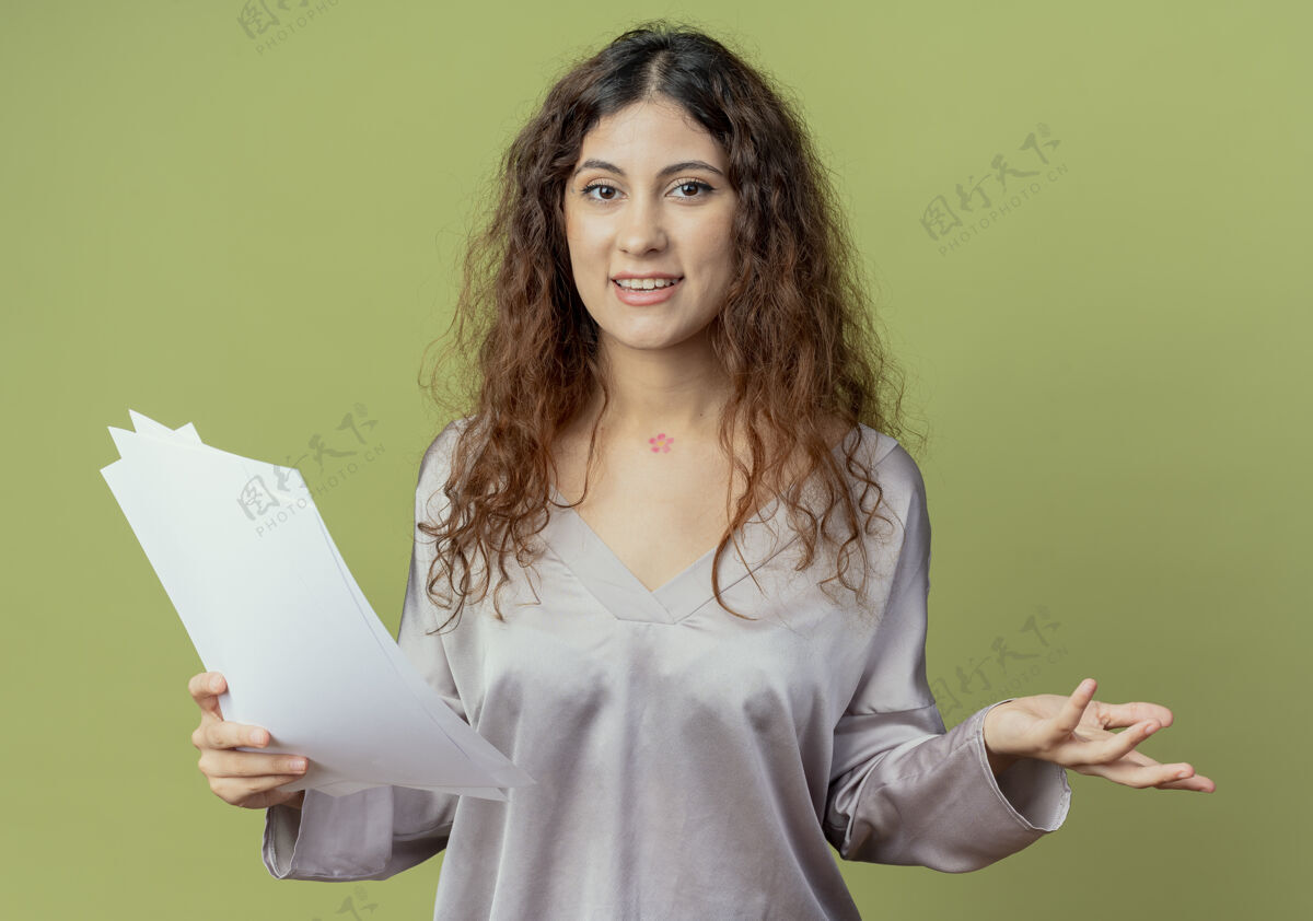 年轻高兴的年轻漂亮的女办公室工作人员拿着文件 摊开橄榄绿墙上孤立的手拿着手纸