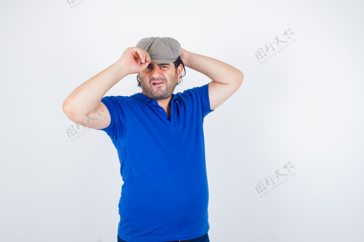 自然中年男子在马球衫 常春藤帽子和优柔寡断的前视图调整他的帽子肖像互联网自行车帽子