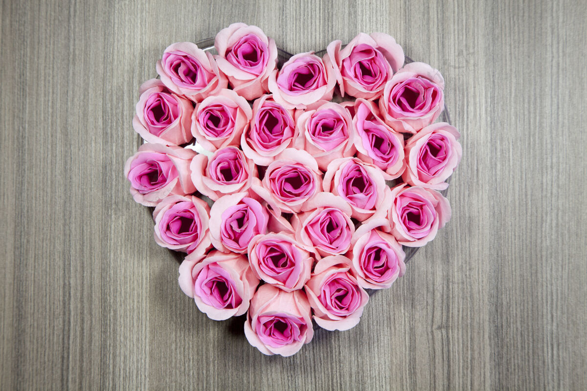 叶高角度特写镜头粉红色玫瑰在一个木制表面的心形束礼物开花