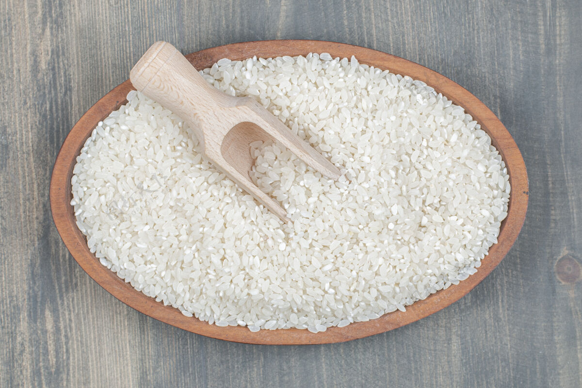 食物健康的生米用木勺放在木桌上烹饪谷物木材
