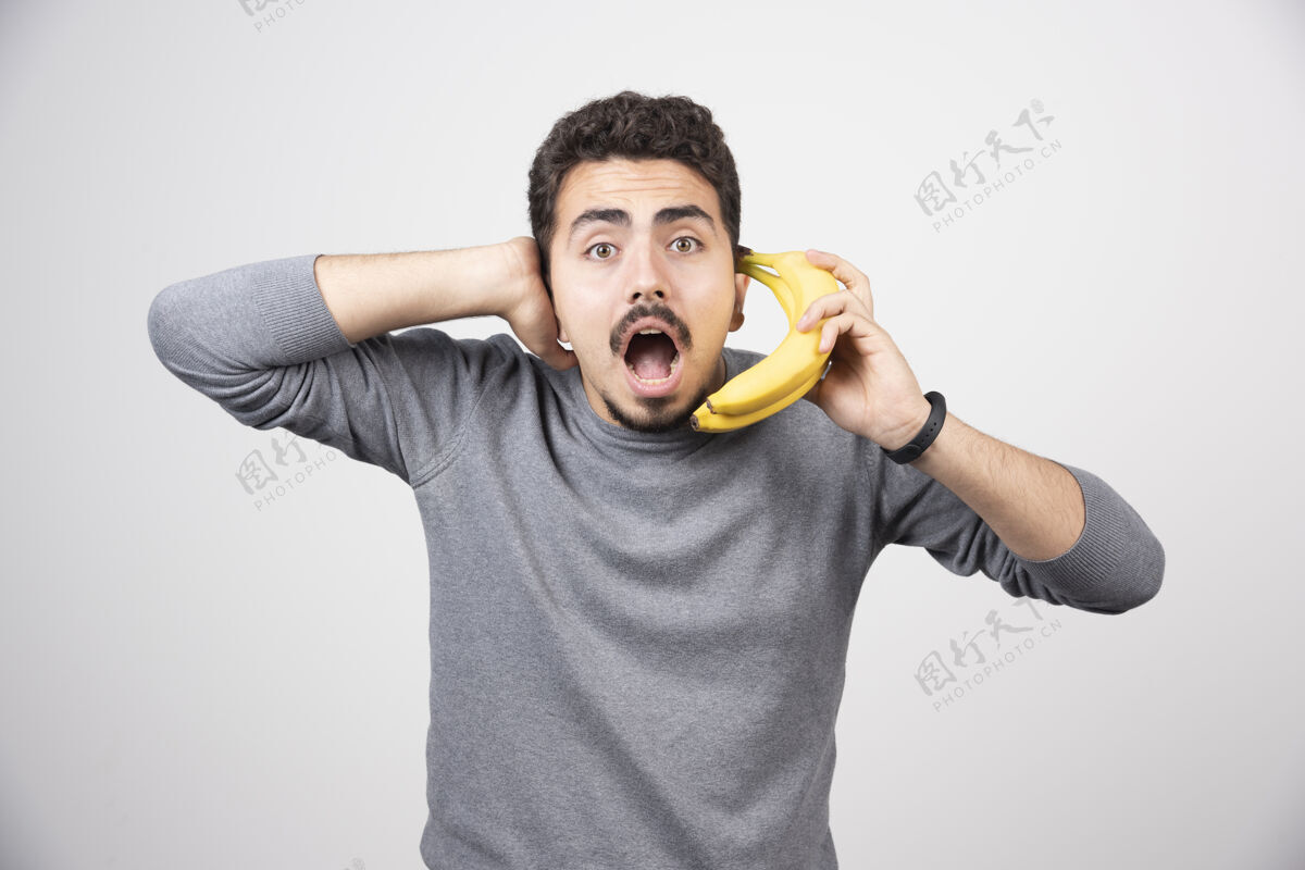 姿势拿着香蕉当电话的黑发男人水果时尚男孩