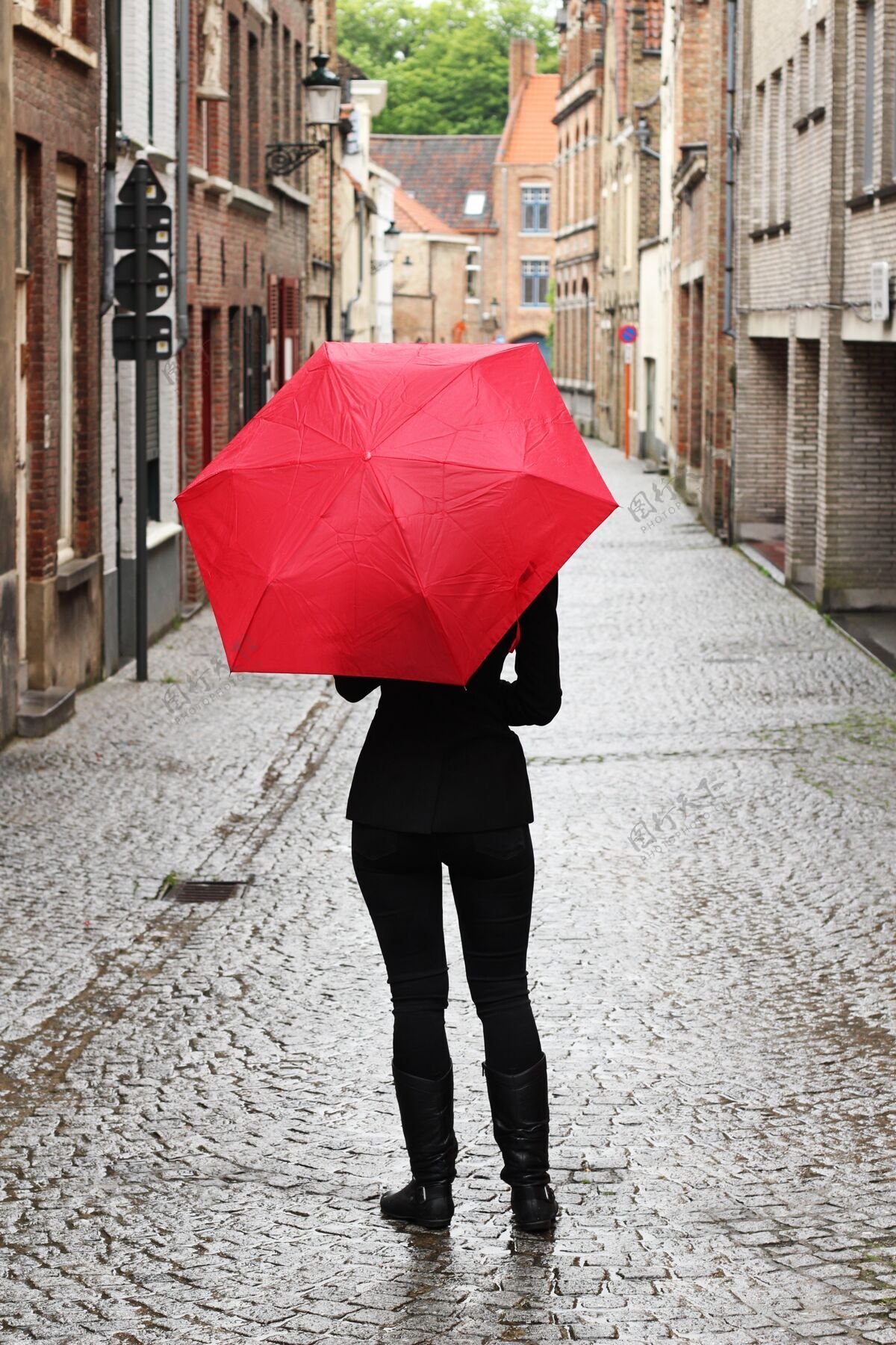 时尚街上一个拿着红伞的女人的垂直镜头美丽年轻背部