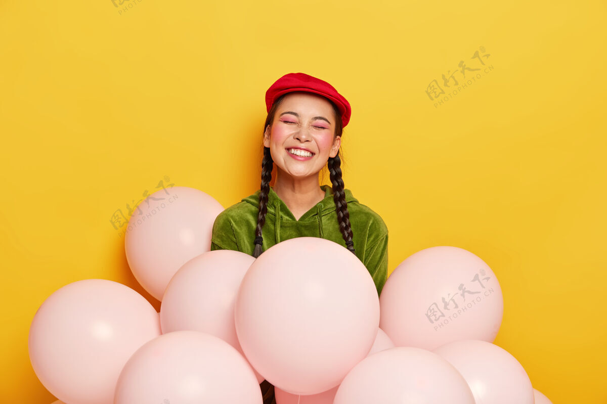 亚洲人喜出望外的漂亮中国女人戴着红色贝雷帽 穿着灯芯绒运动衫 摆着气球的姿势休闲场合情绪