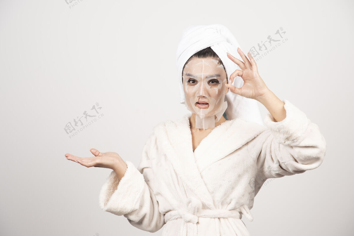 年轻穿着浴衣和带面罩的毛巾的女人清洁皮肤水疗