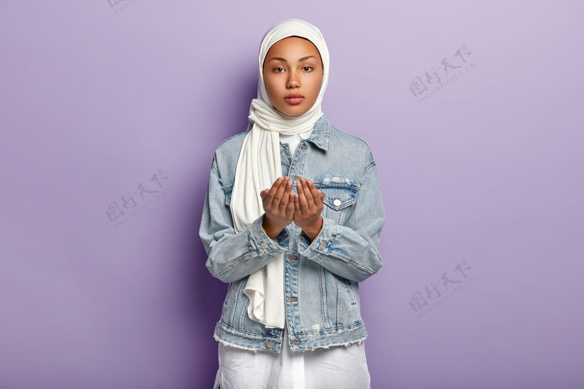 严肃手势和祈祷概念严肃的黑皮肤女性举手祈祷 祈求某事 戴围巾和牛仔夹克 隔离在紫色墙壁上宗教概念头混合面伊斯兰