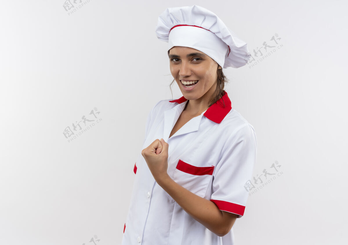 制服微笑的年轻女厨师穿着厨师制服做着强有力的手势与复制空间动作强壮女