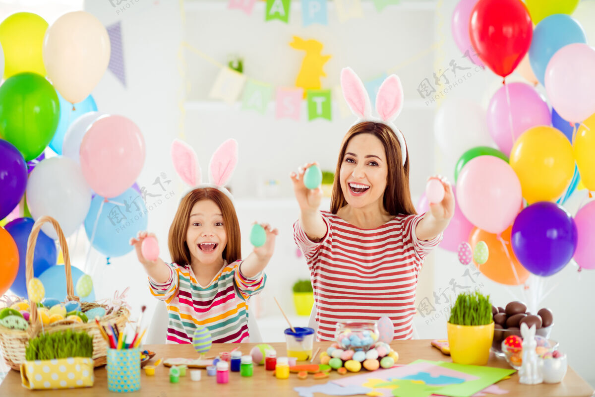 传统两个可爱的可爱的快乐的创意欢快的快乐的女孩的画像小的小的未成年的女儿戴着小兔子的耳朵在白色的光室内房间房子的棍子上展示装饰性的鸡蛋房子班级手工制作