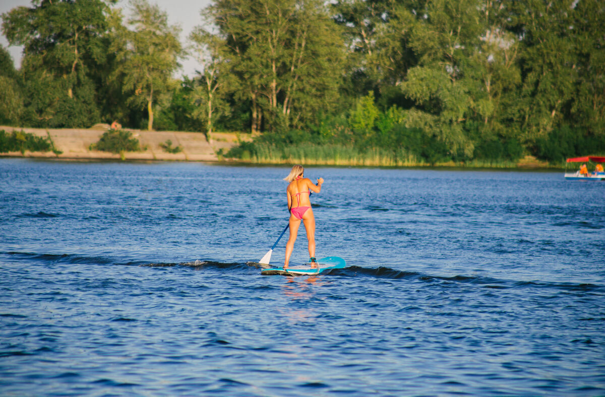 自然在河里的冲浪板上穿着比基尼的年轻美女冥想比基尼教练