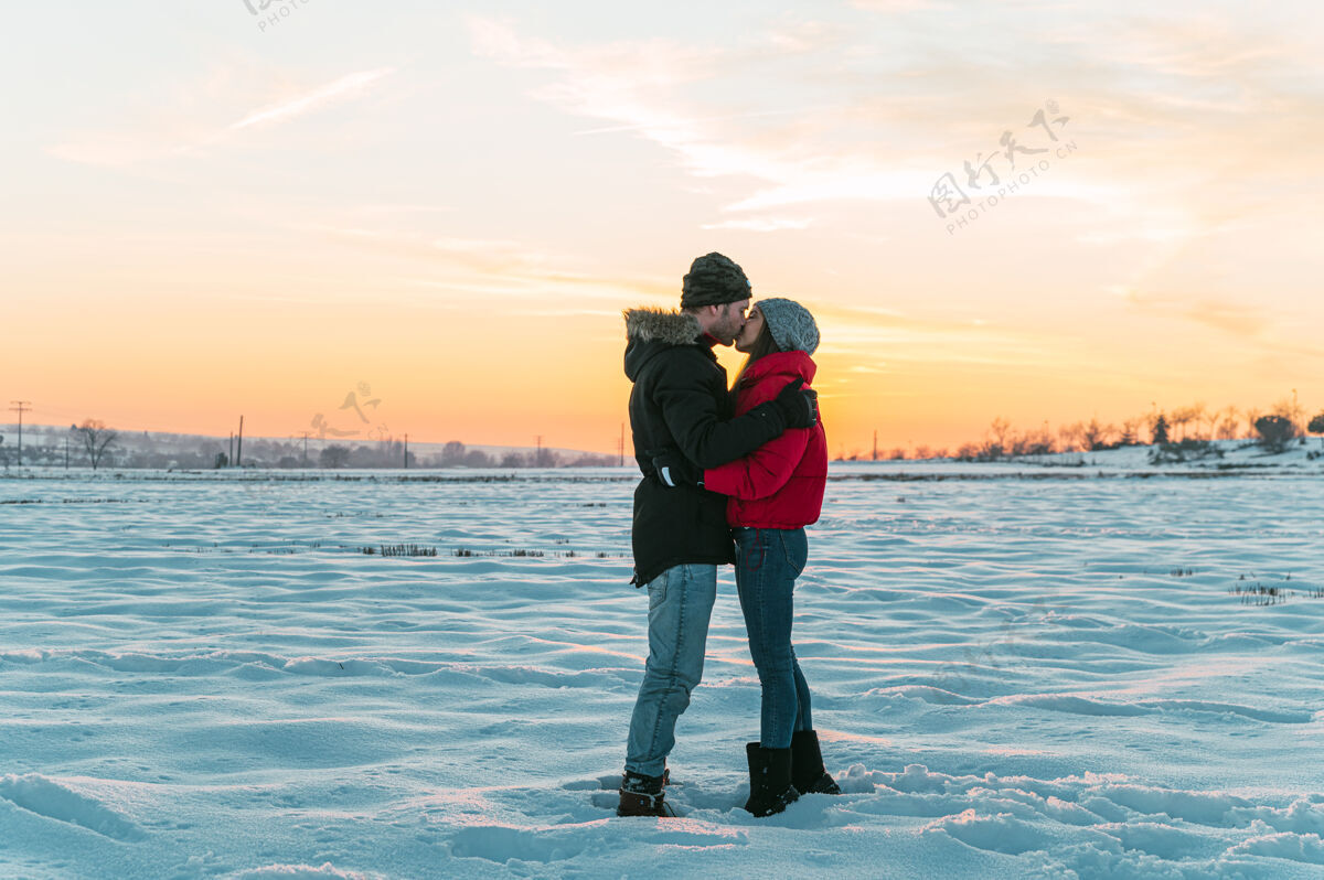 全身一对热恋中的情侣穿着暖和的衣服 在雪域冬日的乡间拥抱亲吻感情雪环境