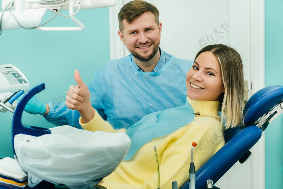 Up美丽的女病人坐在牙医的椅子上 用她的手向全班展示卫生器械女性