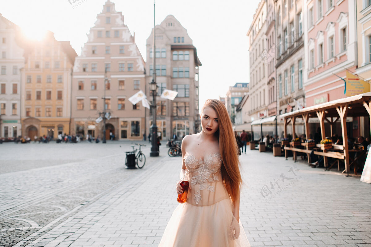 美丽弗罗茨瓦夫老城 一位穿着婚纱 留着长发 拿着酒瓶的新娘在一个古老的波兰中心拍摄婚纱照弗罗茨瓦夫市 波兰房子奶油酱市中心