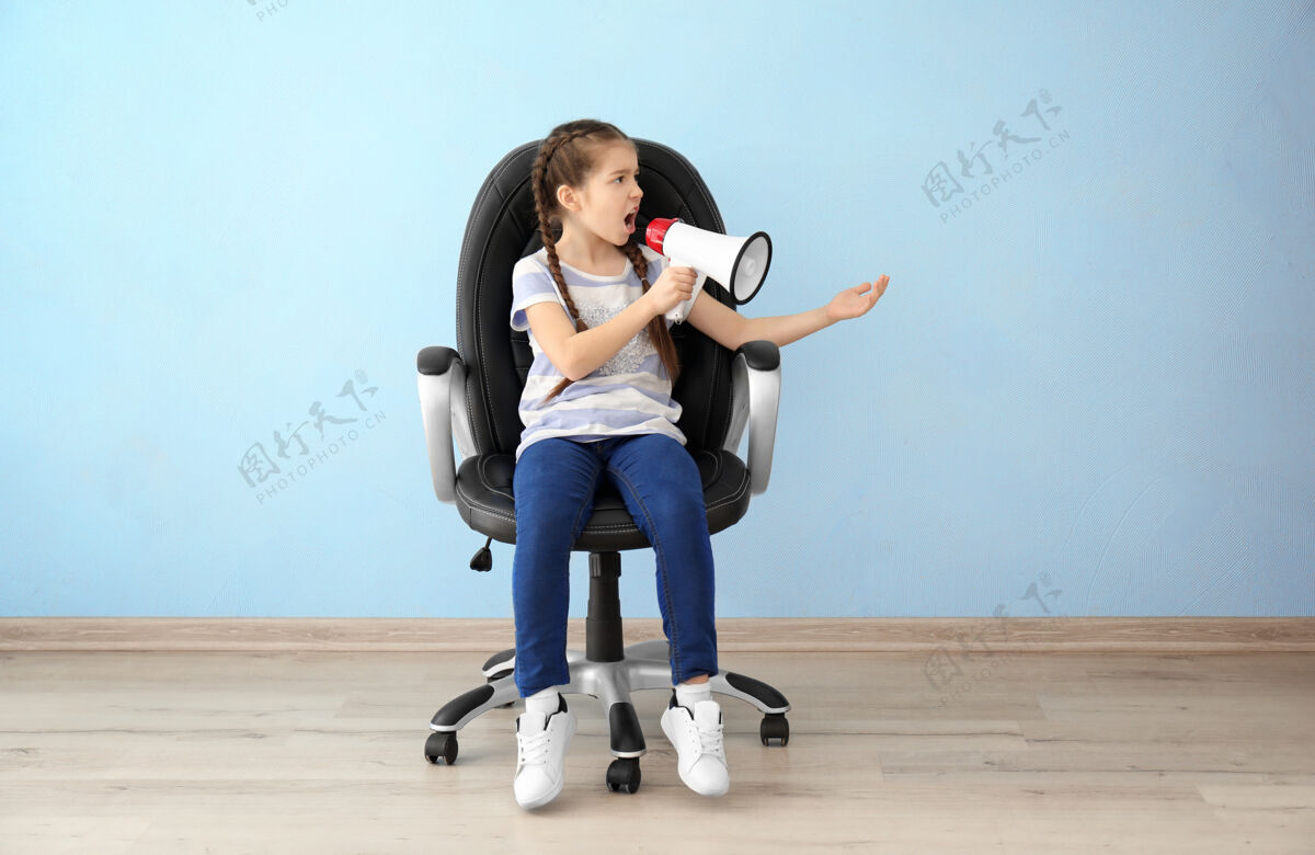 公众情绪激动的小女孩拿着扩音器坐在空房间的椅子上愤怒领导情绪