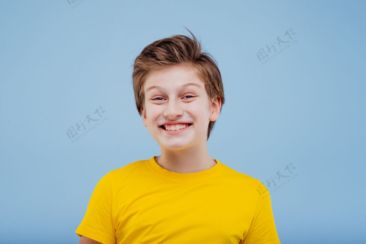 孩子可爱的微笑着的小男孩 穿着黄色的t恤隔离在蓝色的墙上 复制空间积极小表情