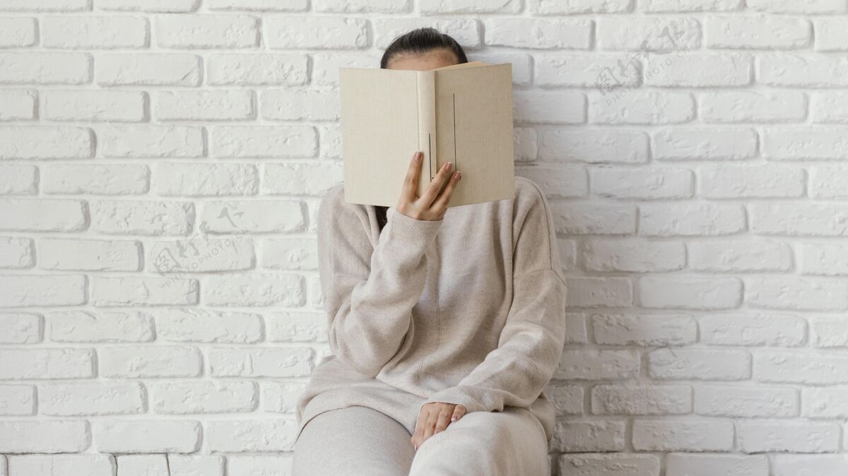 信息中等身材的女人用书遮住脸年轻女性阅读