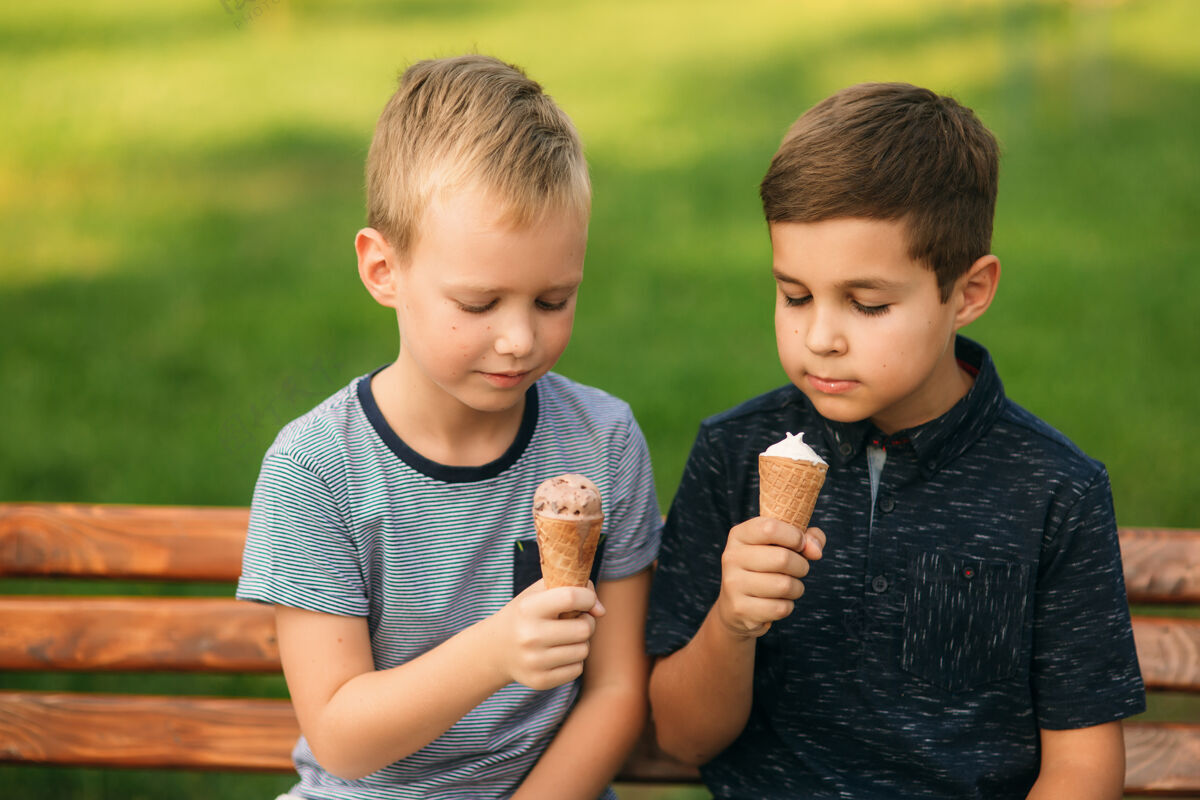 肖像两个孩子在公园里玩两个穿着t恤和短裤的漂亮男孩笑得很开心男孩友谊长凳