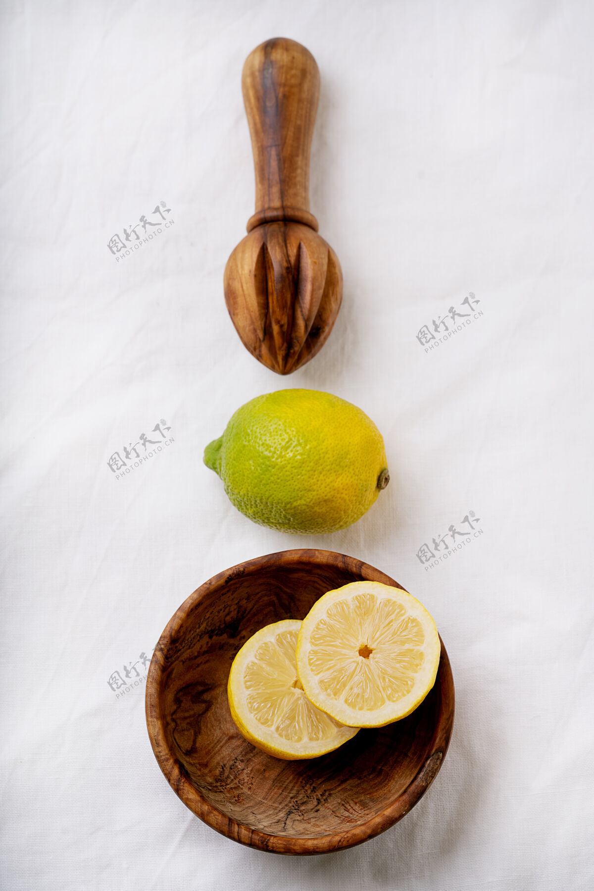 顶部柠檬在木制碗与木制挤压器切成两半白色织物表面顶视图平铺复制空间有机水果食物