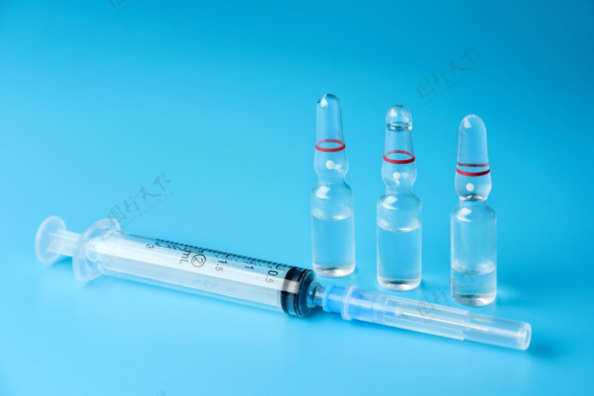 瓶子注射器和三个玻璃安瓿 蓝色表面有药物安瓿化学药品