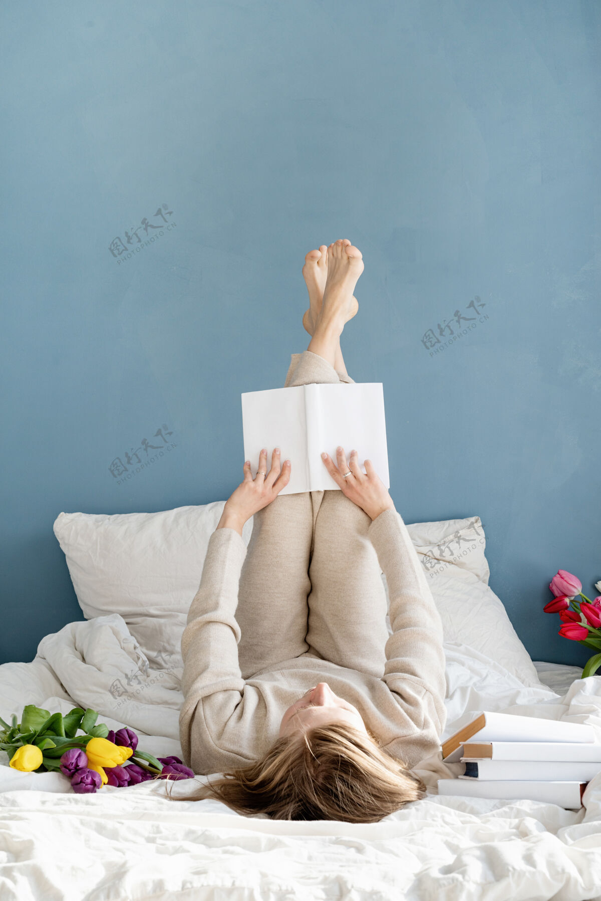 情人节快乐微笑的女人穿着睡衣坐在床上 愉快地赏花看书笑浪漫微笑