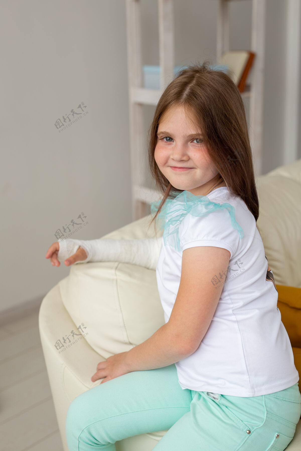 破裂手腕或手臂受伤的孩子在沙发上微笑着玩耍积极的态度沙发房子人类