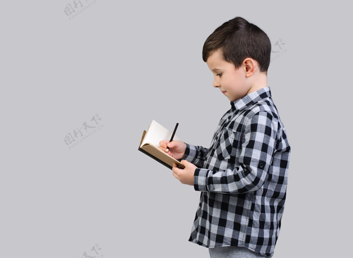 小学生一个穿着灰色衬衫的小学生在笔记本上写字手持休闲服头像