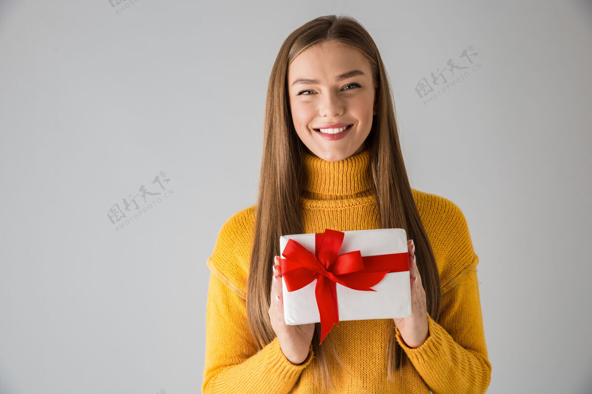 肖像一个美丽快乐的年轻女子举着礼品盒隔着灰色的墙 独自一人休闲爱情吸引力