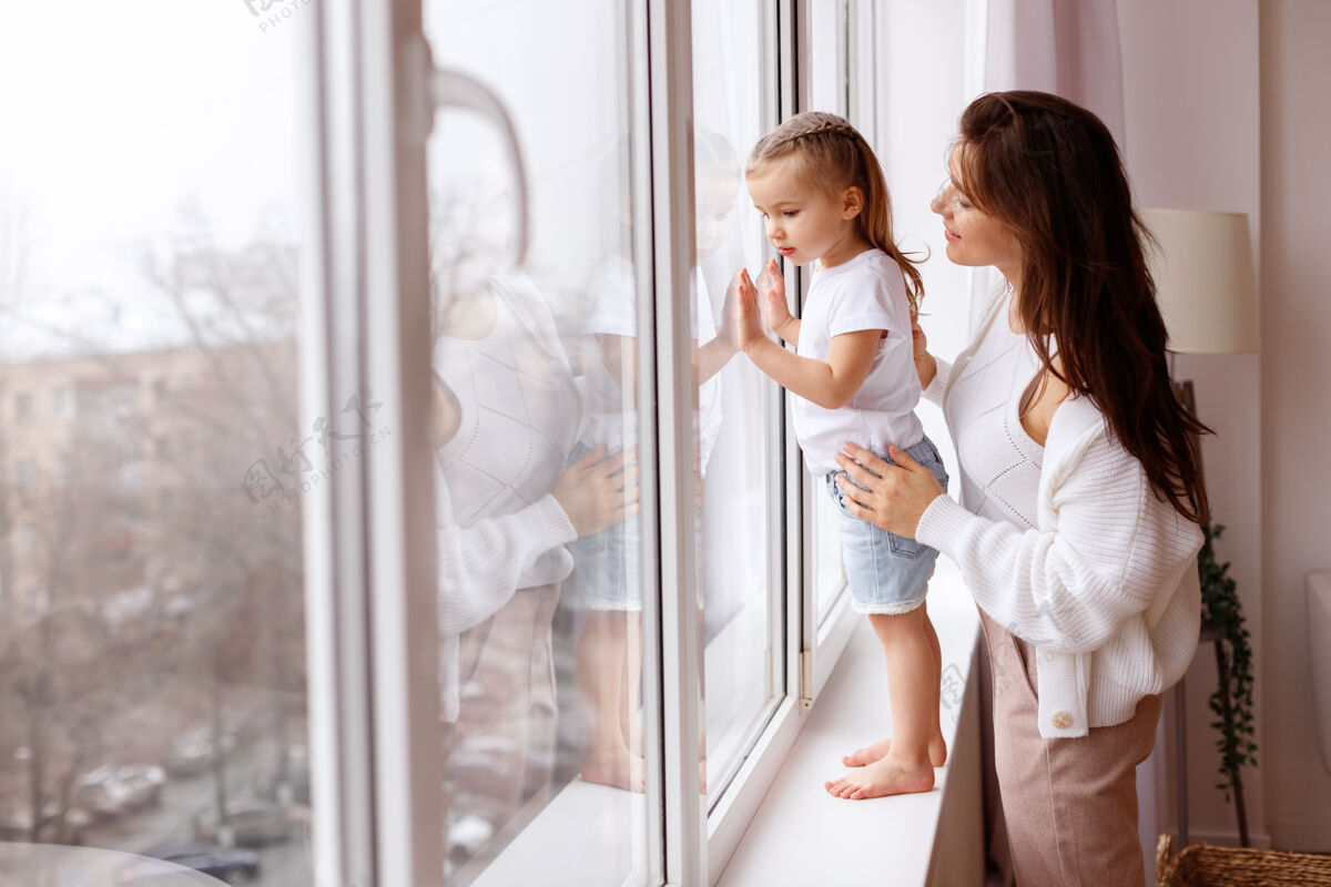 孩子妈妈和女儿看着窗外宝贝年轻妈妈