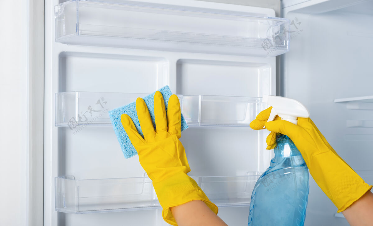 消毒一个女人的手戴着黄色的橡胶防护手套和蓝色的海绵在清洗冰箱货架.清洁服务 家庭主妇 日常事务家务.喷雾窗户和玻璃表面更干净细菌清洁剂房子