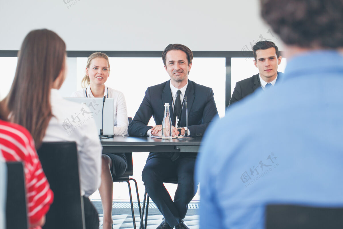 会议商务会议上的演讲者们带着麦克风坐在桌边大会研讨会男性