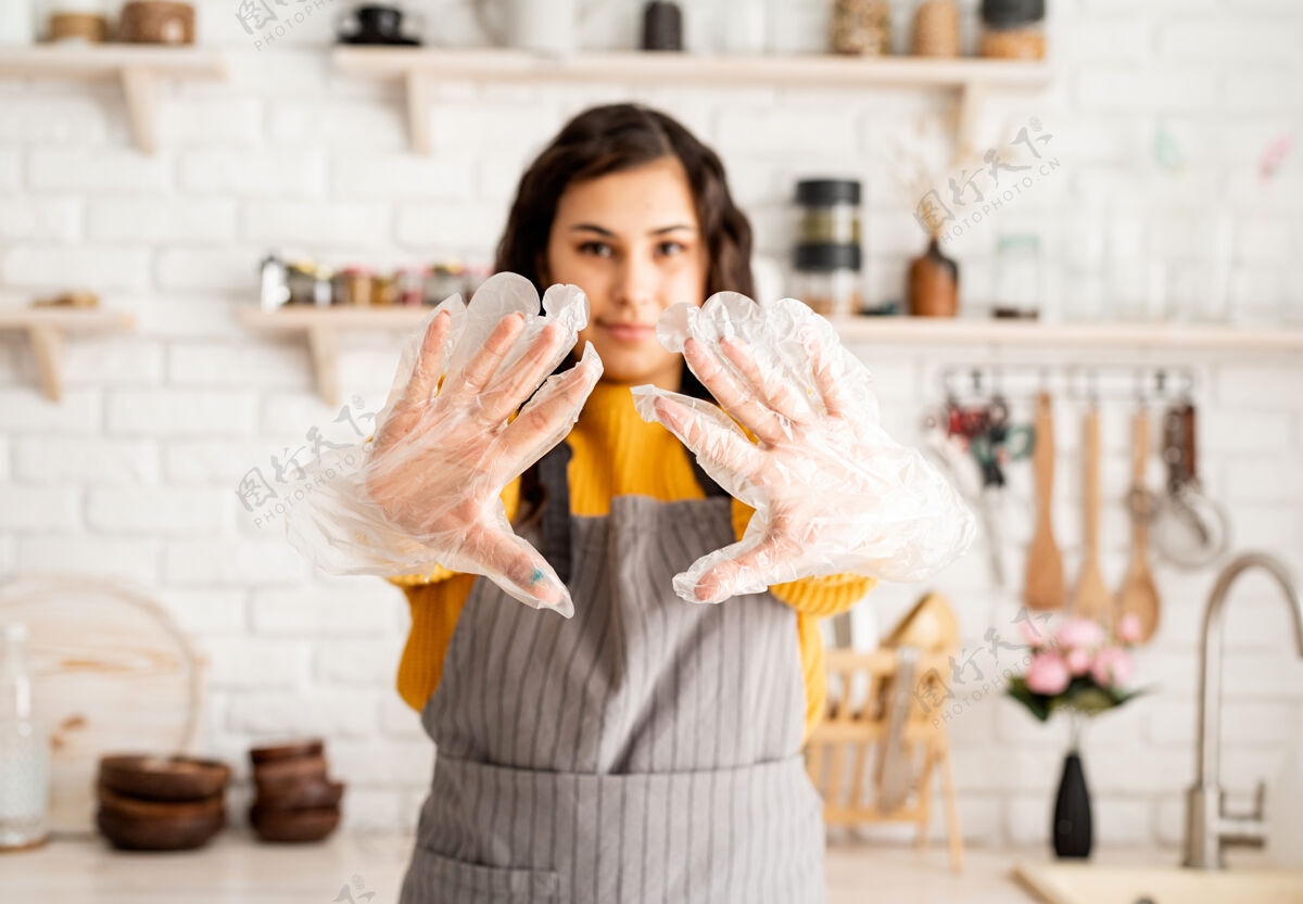油漆穿着黄色毛衣和灰色围裙的黑发美女准备在厨房给复活节彩蛋上色戴上手套装饰孩子围裙