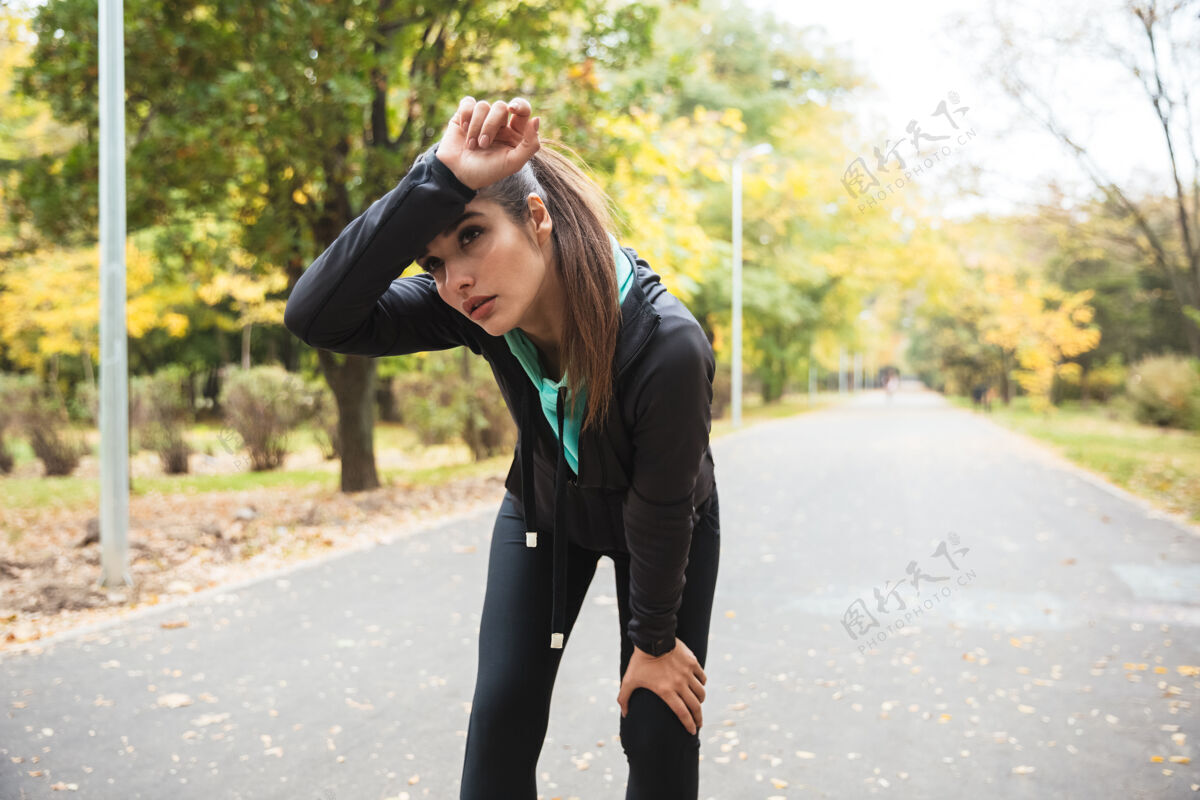 放松一个美丽的年轻漂亮的健身女跑步者在公园户外休息的形象运动员身体瑜伽