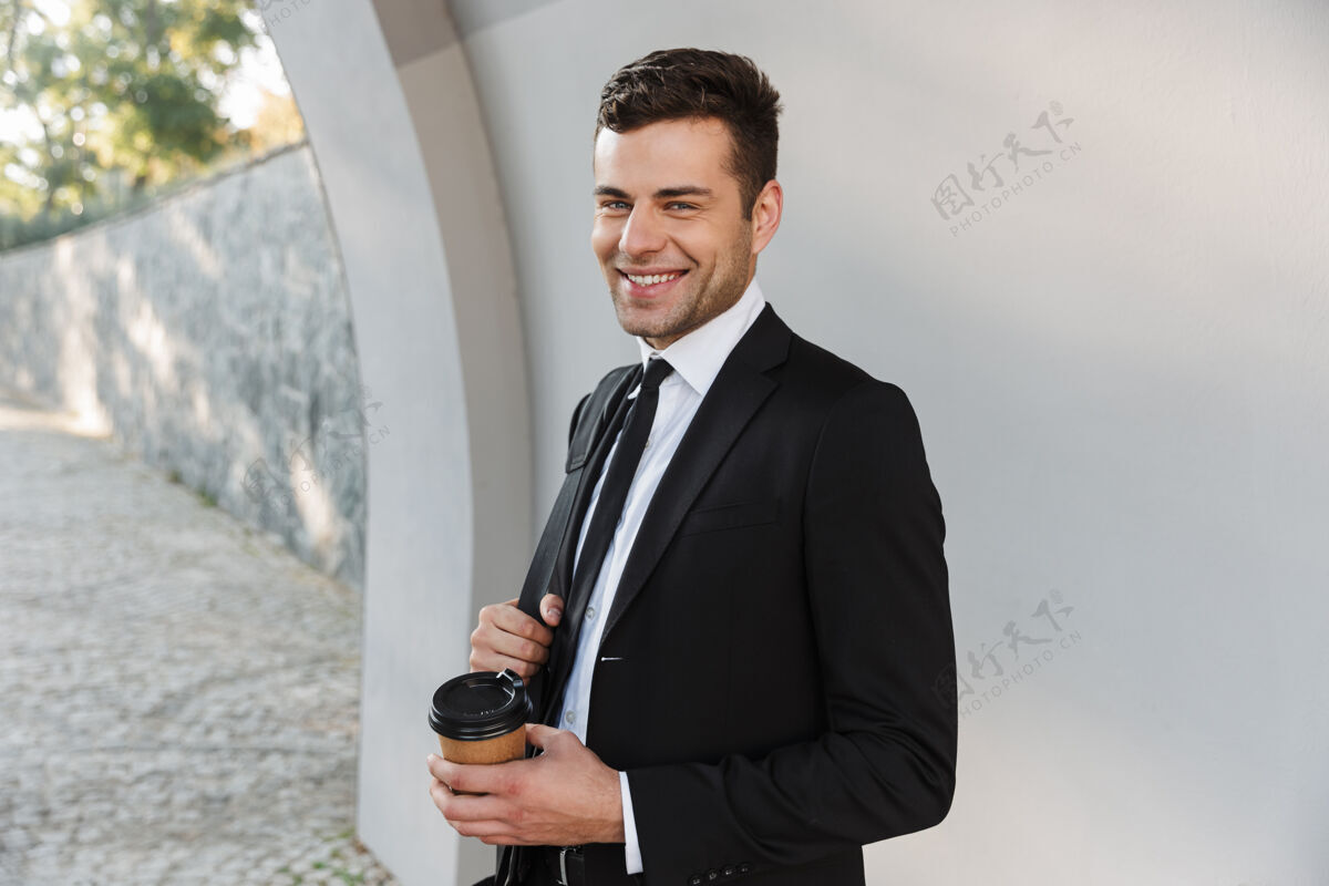 高管穿着正装的年轻帅哥商人在街上喝咖啡的照片工人年轻事业
