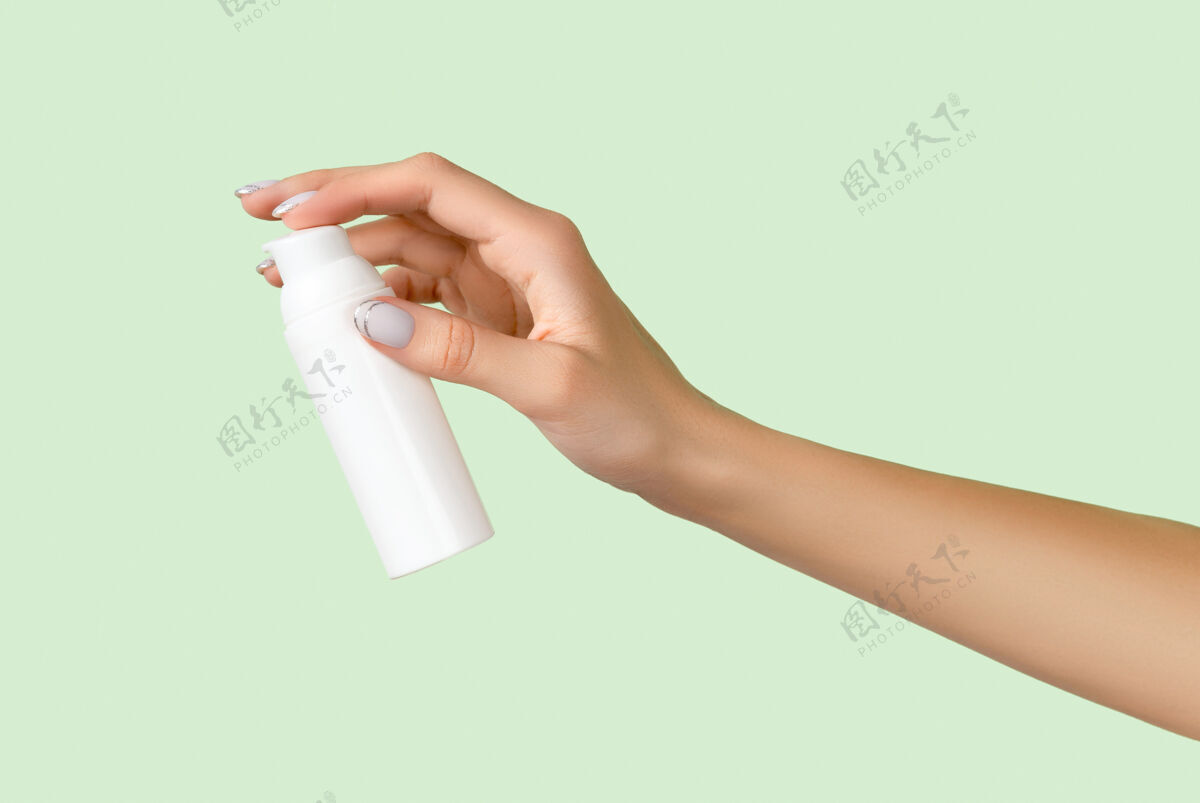 产品女人的手拿着淡绿色的白色瓶子面霜瓶子护肤常规