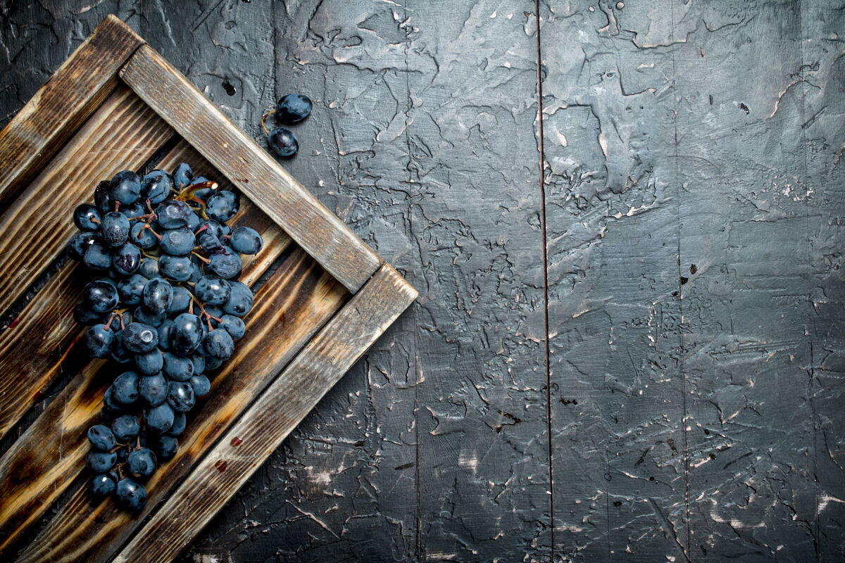 一串黑葡萄放在木托盘上葡萄园健康的营养