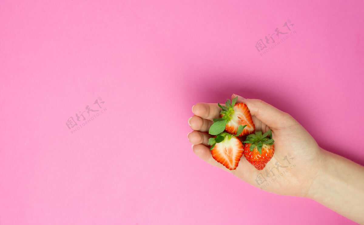 背景一只手拿着粉红草莓的雌手背景.平坦躺着横幅.space为了文本.摘要.!背景 叶子 女人 水果 草莓 手指 甜点 饮食 年轻 新鲜 零食 种子 浆果 美食 切割 收获 美味 开胃菜 一半 切片 多汁 欲望 手