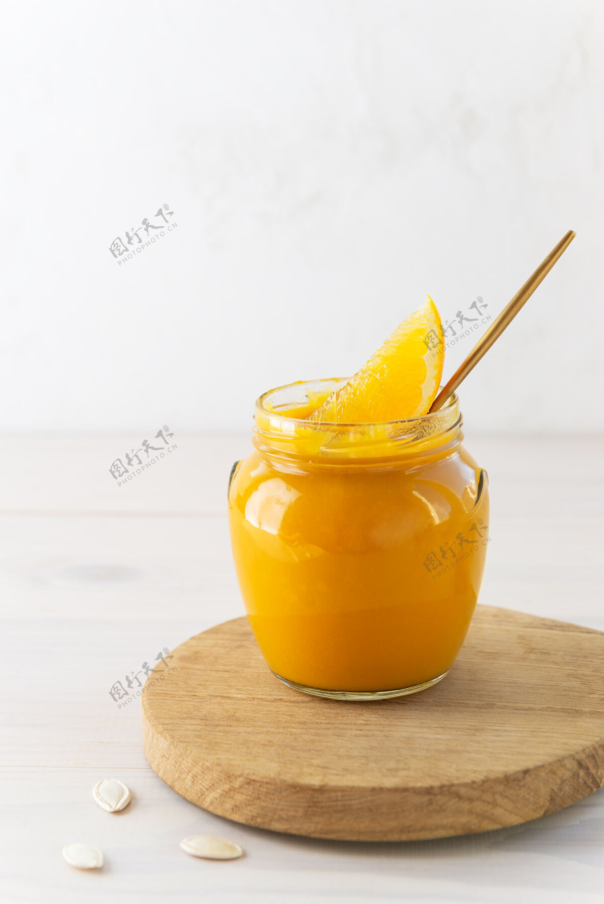 勺子南瓜果酱和橘子放在一个玻璃罐里放在一块板上纯有机烹饪