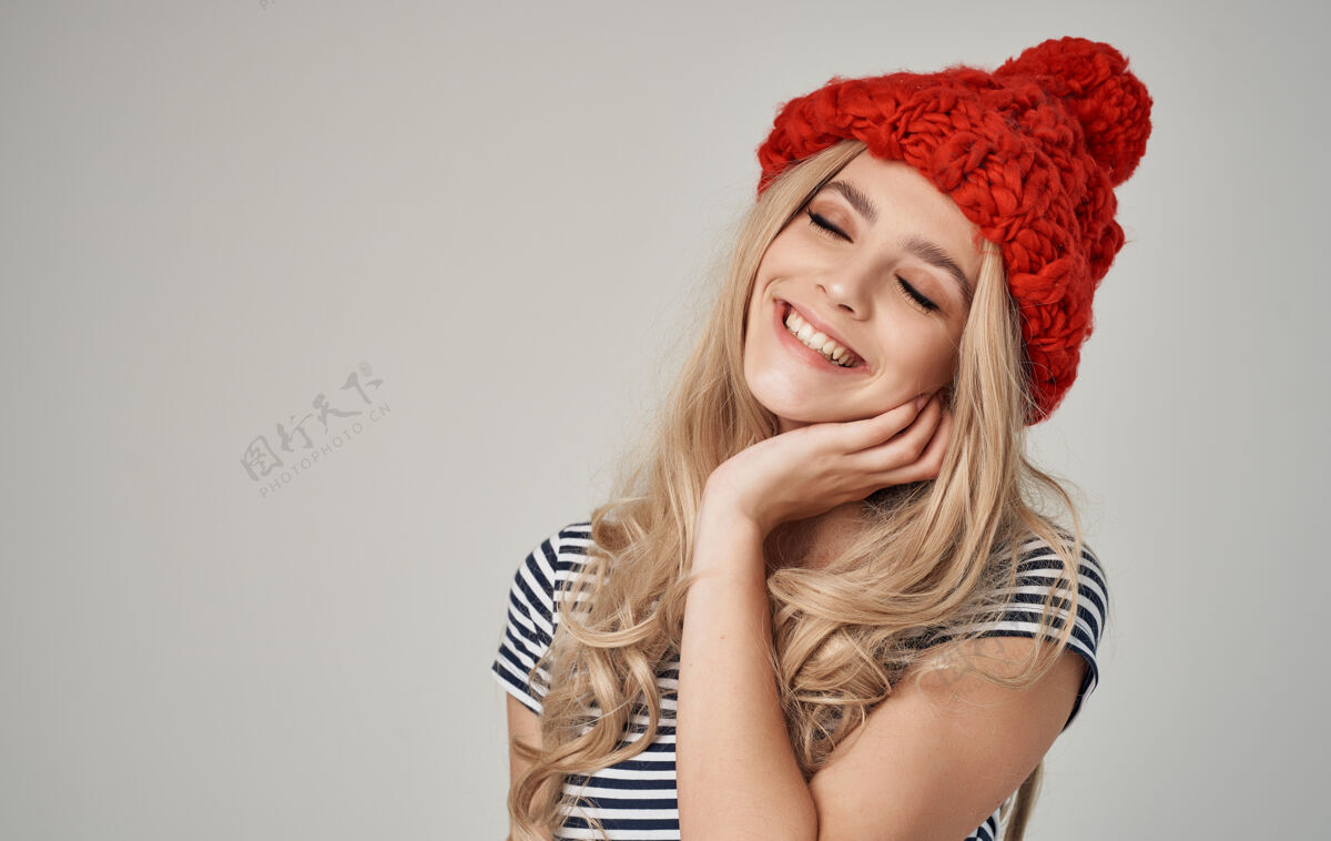 休闲穿着红色针织帽子和条纹t恤的性感金发女郎不规则剪裁的特写镜头漂亮帽子魅力