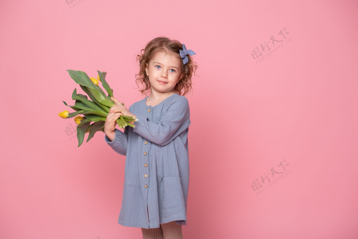 孩子美丽的金发小女孩穿着蓝色的裙子 粉色的裙子上有一束黄色的郁金香郁金香童年惊喜