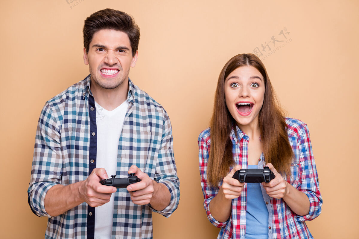 生活方式照片中有趣的时髦夫妇两人玩电子游戏与女友击败他的男朋友笑在愤怒的米色粉彩背景孤立心烦男人朋友