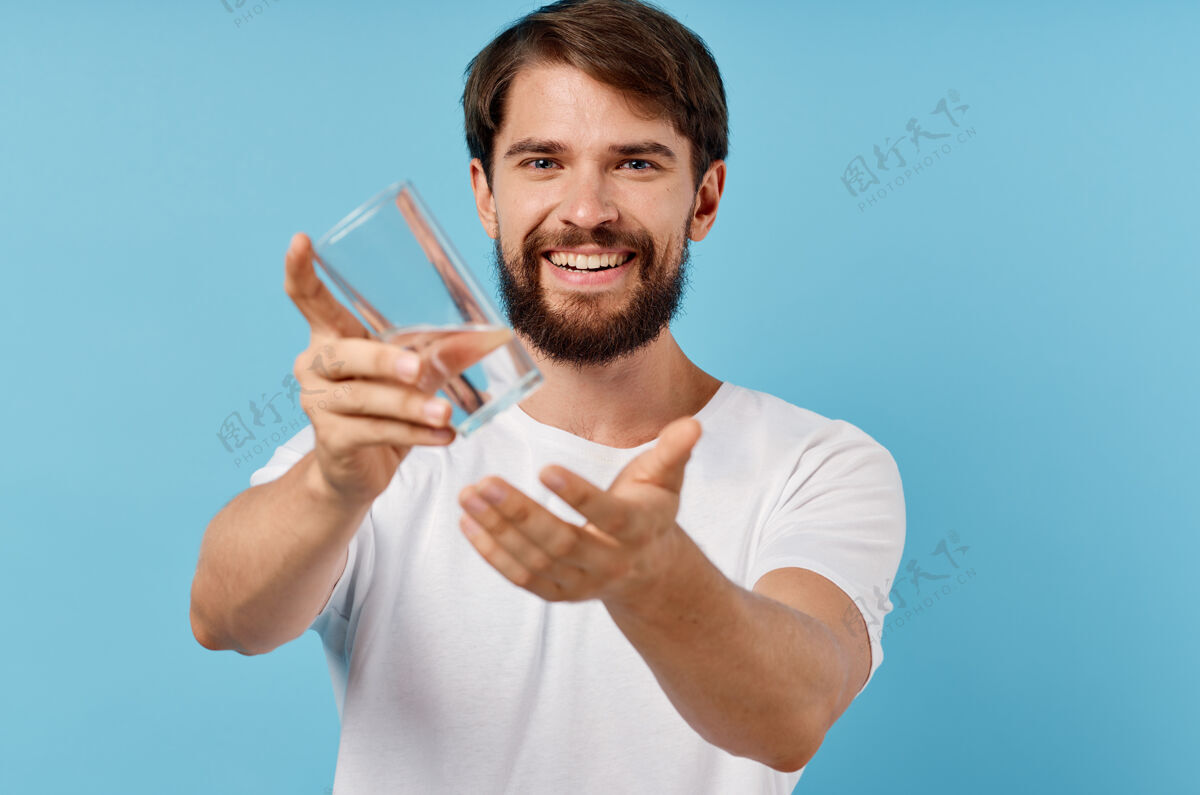 纯净快乐的男人用一杯水在蓝色的背景上喝生活方式人水玻璃