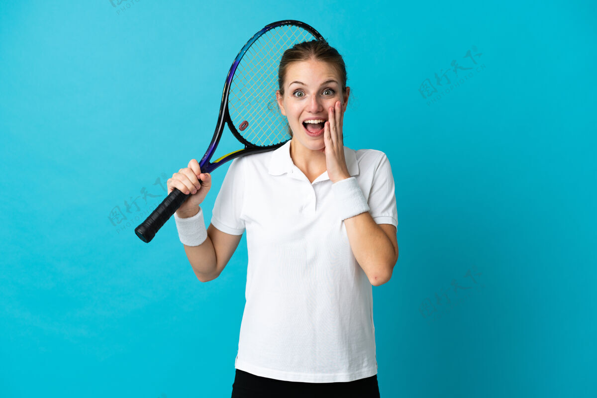 兴奋年轻的女子网球选手被隔离在蓝色背景下 脸上露出惊讶和震惊的表情休闲哇年轻