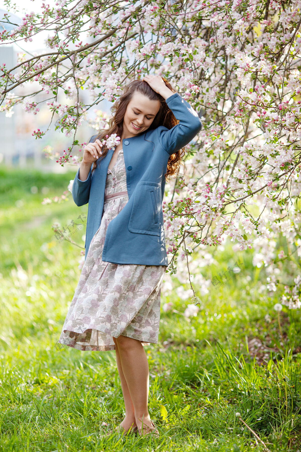 黑发春天 一位身穿蓝色夹克的黑发美女在苹果树花园里的画像时间好好享受自然健康微笑的女孩室外.春季概念漂亮果园里的女孩快乐快乐开花