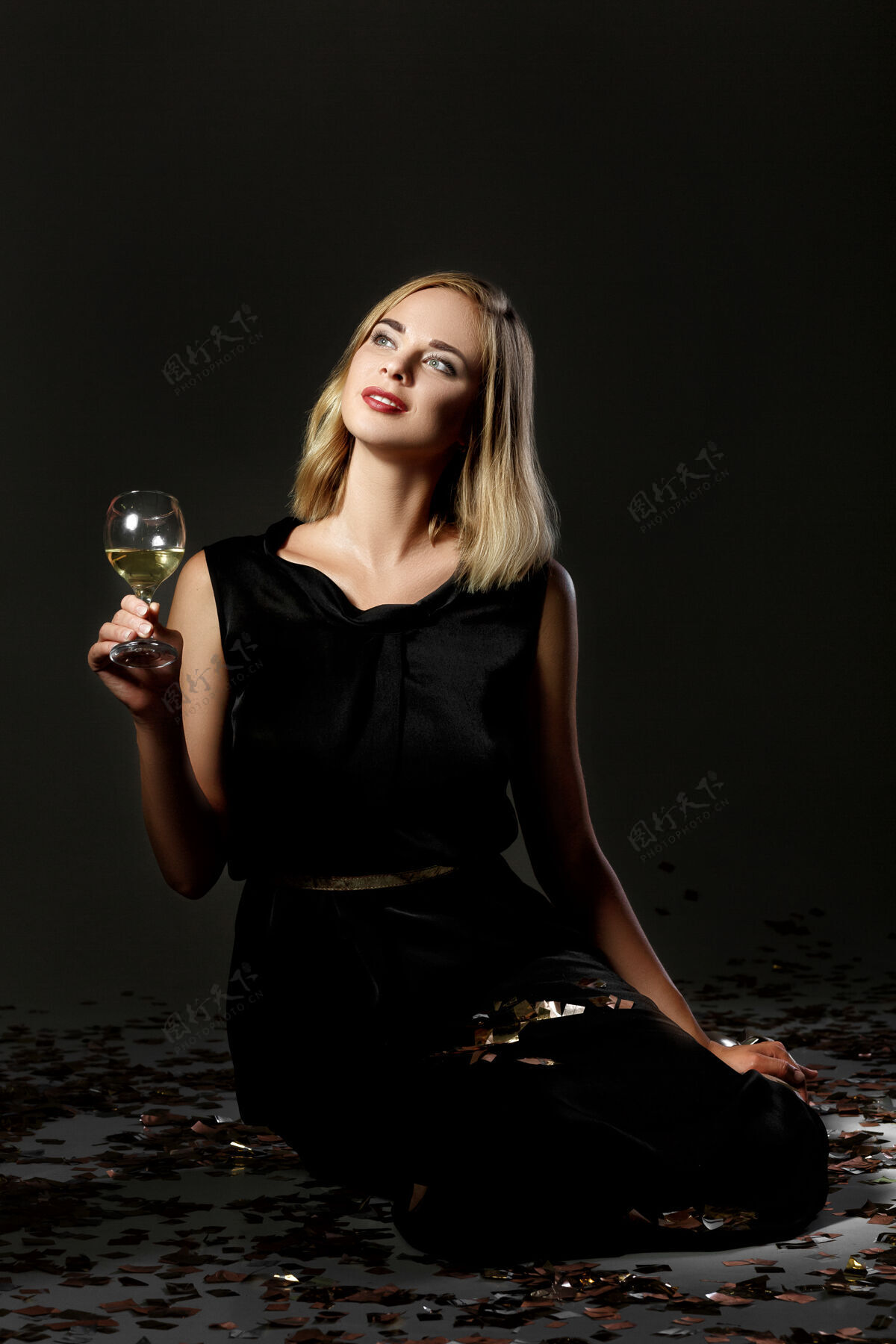闪亮美丽的金发女人 一杯黑底白葡萄酒年闪光白色