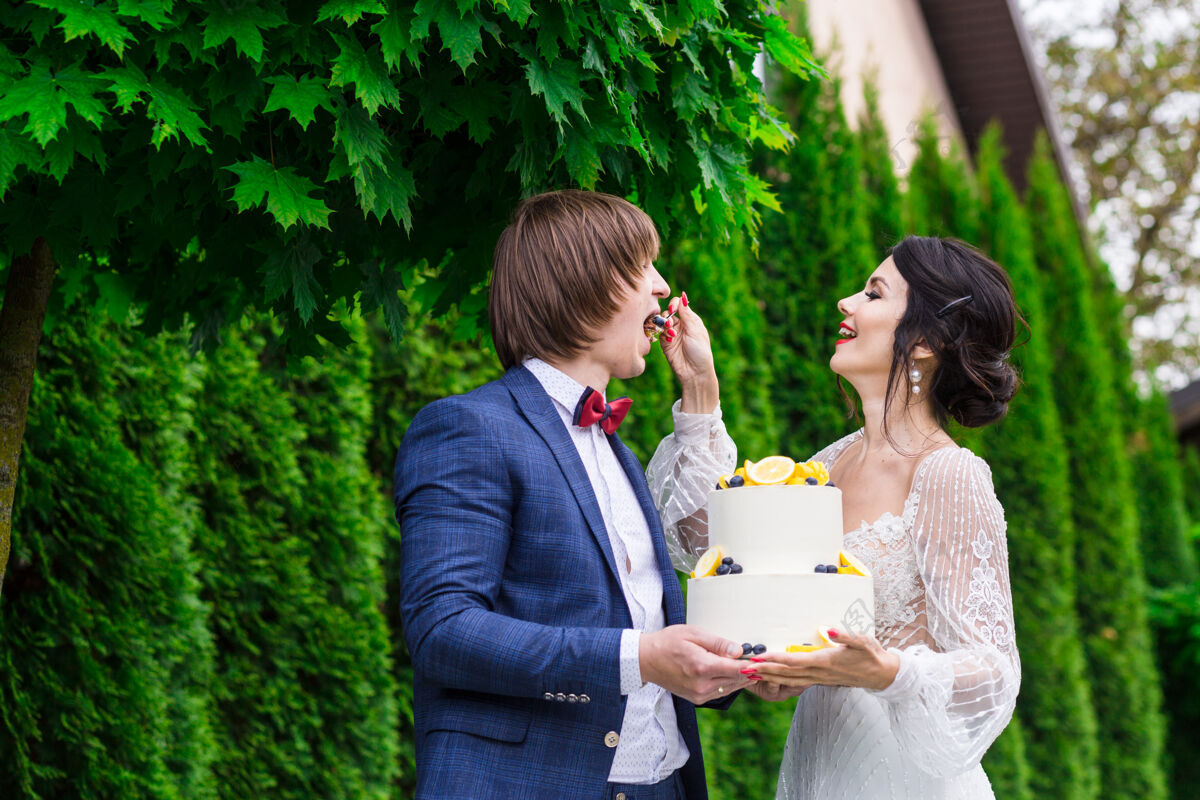 甜点新婚夫妇和伴娘们在婚宴上尽情享受 在新鲜空气中一起吃结婚蛋糕接待聚会夏天