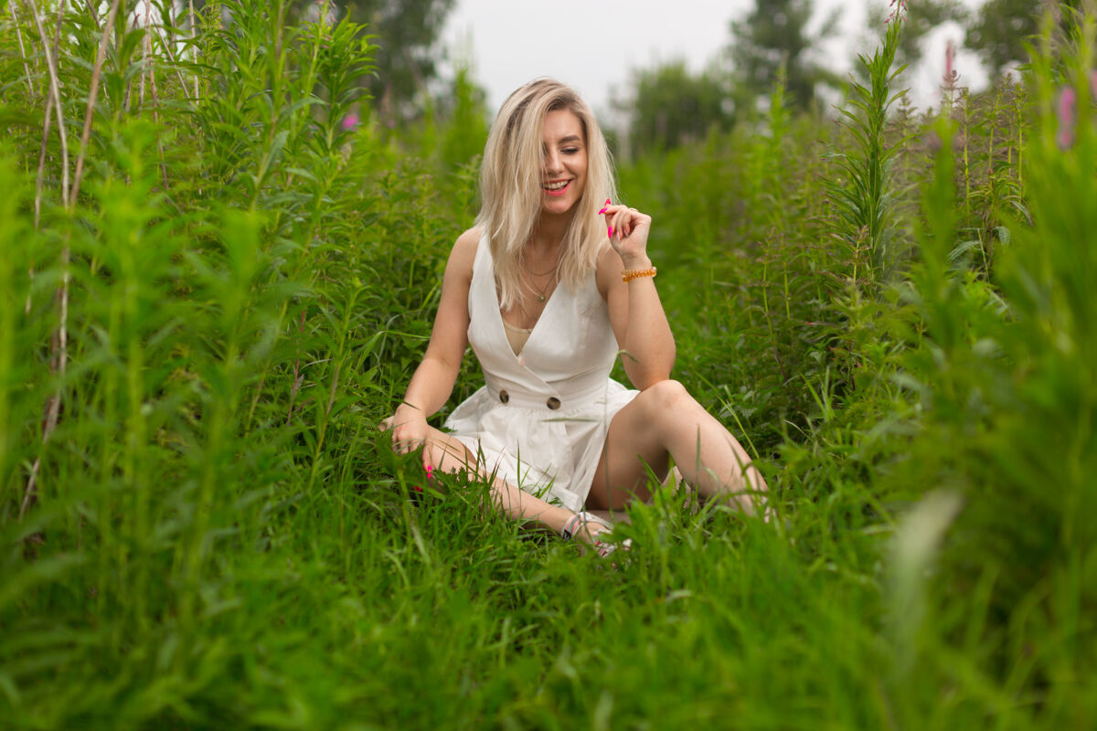 坐着一个穿着白色夏装的金发女孩坐在高高的草地上成人女人美丽