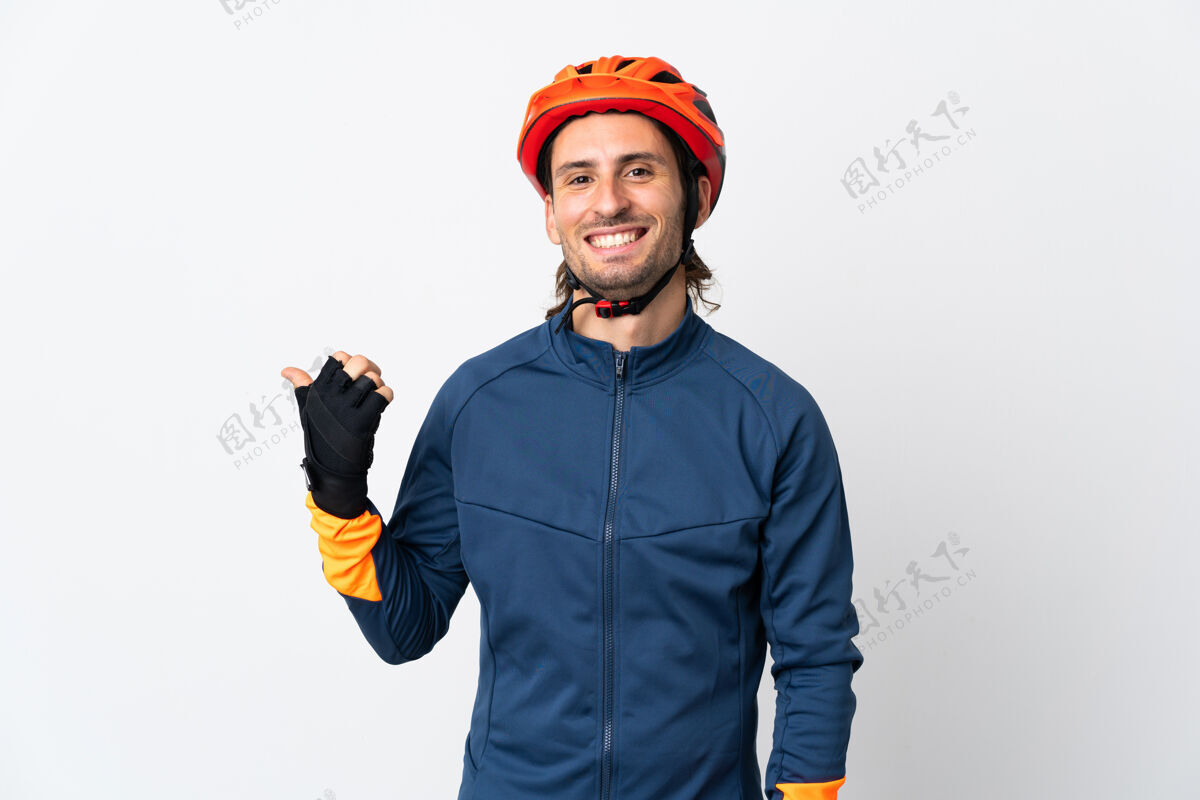 方向年轻的骑自行车的男子孤立地站在白色的墙上 指着旁边的产品展示表情骑人