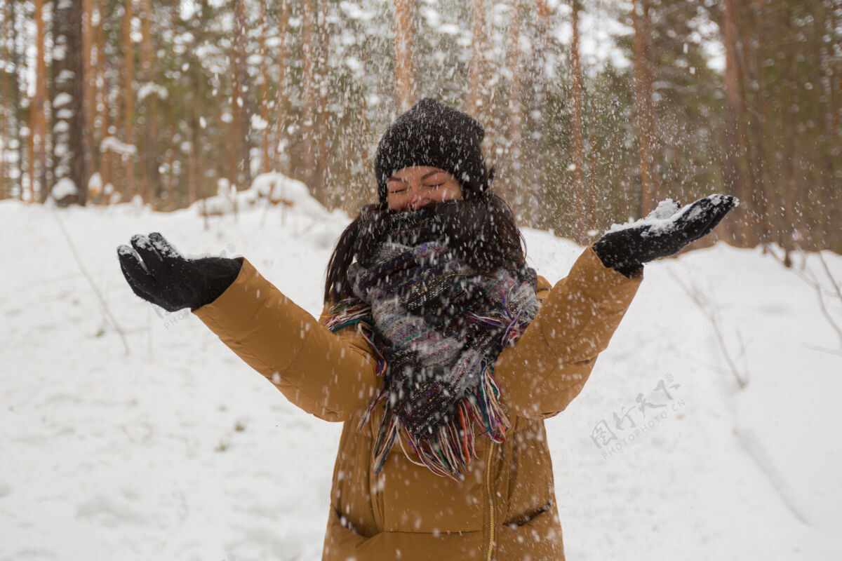 自然一个戴着黑帽子和棕色夹克的小女孩在冬天的森林里玩雪下雪冰冻冬天